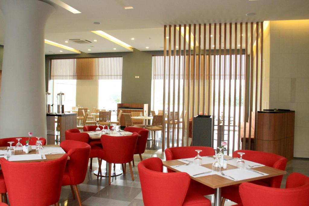 a restaurant with red chairs and tables in a room at Kyriad Hotel Airport Jakarta in Tangerang
