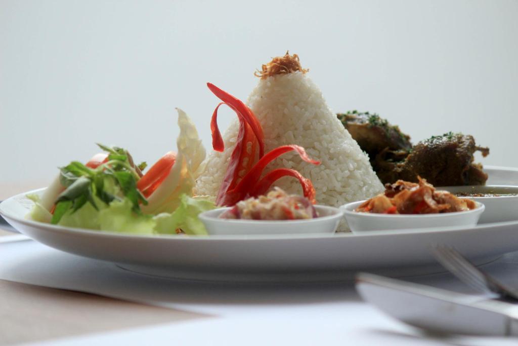 a plate of food with rice and vegetables on a table at Kyriad Hotel Airport Jakarta in Tangerang