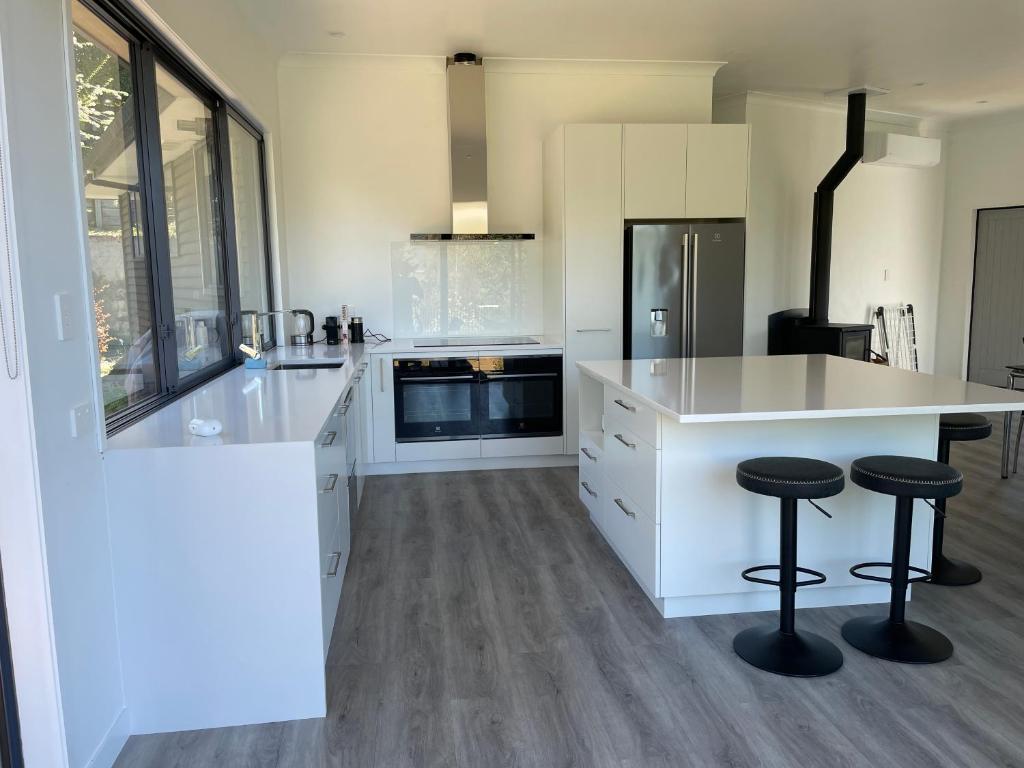 een keuken met witte kasten en een aanrecht met krukken bij Private Retreat Central Wanaka 2 Bedroom in Wanaka