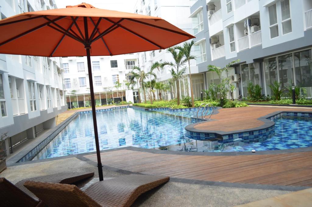 an umbrella and chairs next to a swimming pool at Kyriad Hotel Airport Jakarta in Tangerang