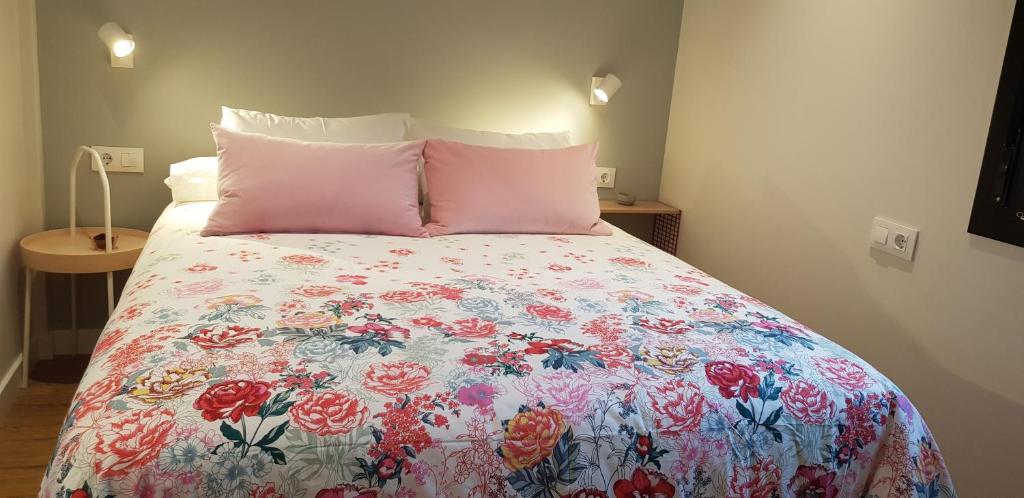 a bed with a floral bedspread and two pink pillows at O Feixoal in Hio