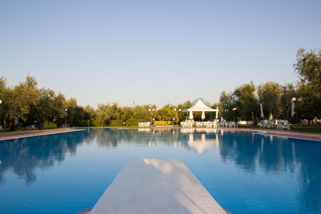 a large pool of blue water in a park at Giardino Degli Ulivi Resort Masseria in Margherita di Savoia