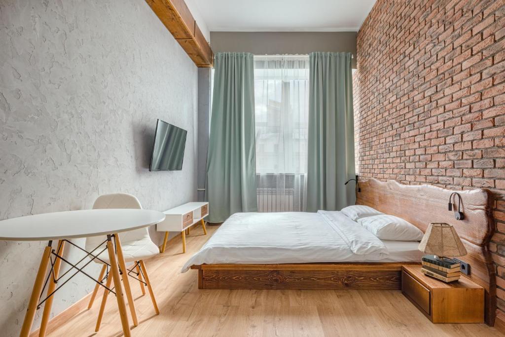 a bedroom with a brick wall and a bed and a table at Отель Впечатления in Yekaterinburg