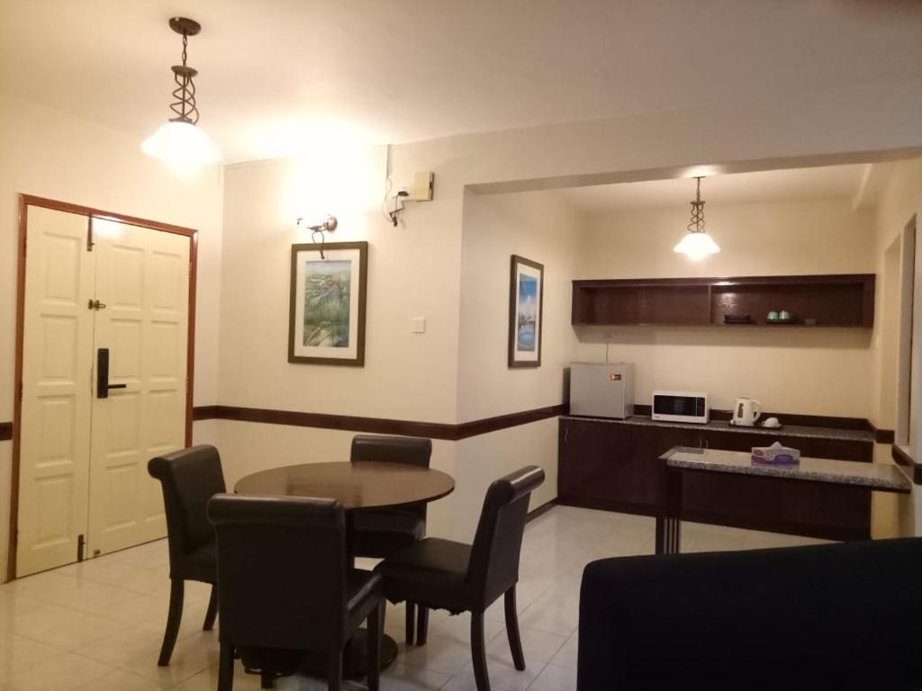 uma sala de estar com mesa e cadeiras e uma cozinha em D Savoy @ A'Famosa by RK em Malaca