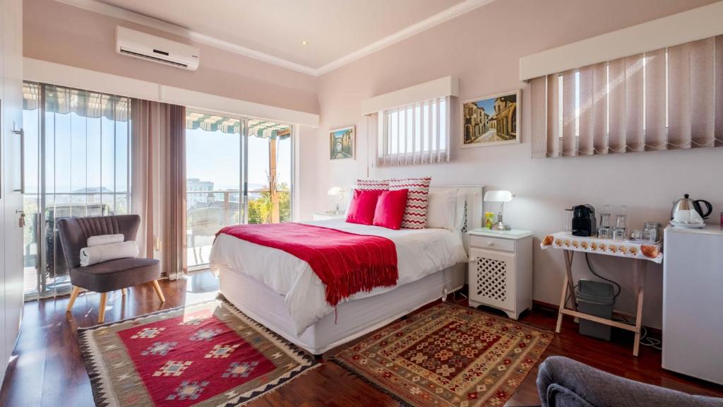 a bedroom with a large bed with red pillows at Anchor Bay Guest House in Cape Town