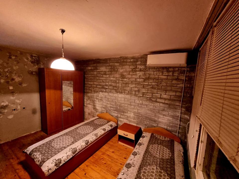 een kamer met 2 bedden en een bakstenen muur bij три стаен лукс апартамент in Razgrad