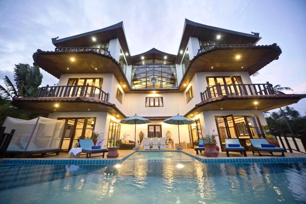 a large house with a swimming pool in front of it at Paradise Island Estate in Choeng Mon Beach