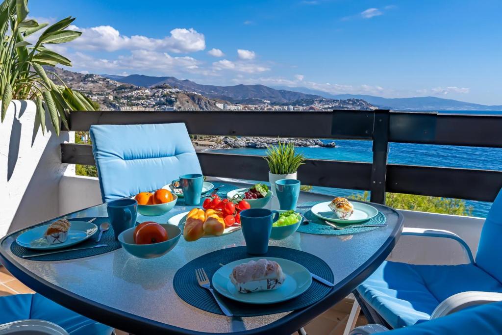 uma mesa com comida numa varanda com vista para o oceano em Casa de Luz em La Herradura