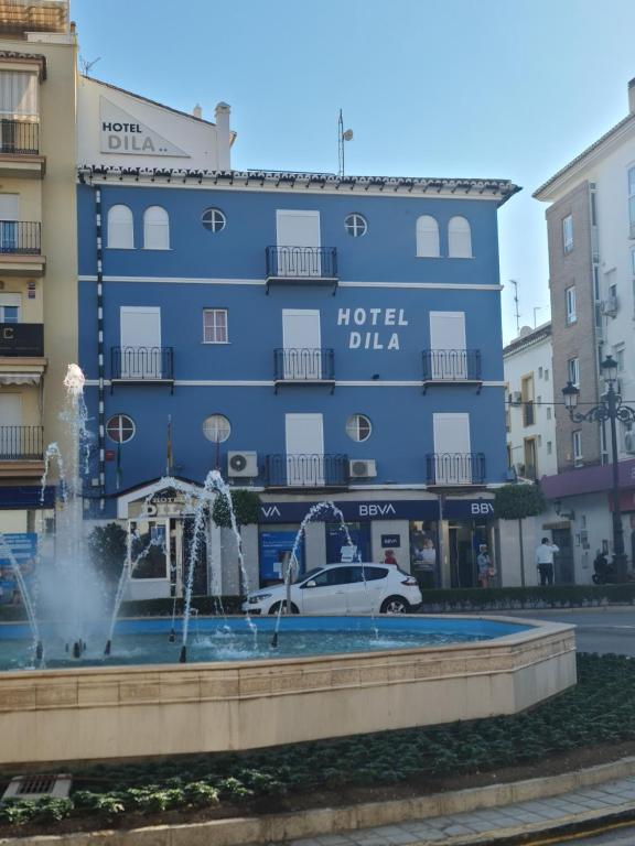 a blue hotel with a fountain in front of it at Hotel Dila in Vélez-Málaga