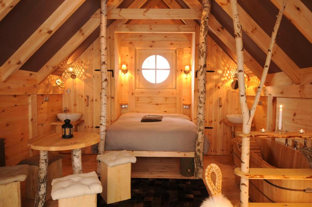 sypialnia w drewnianym domku z łóżkiem i wanną w obiekcie Cabane Lodge Domaine du Lac Chambon w mieście Murol