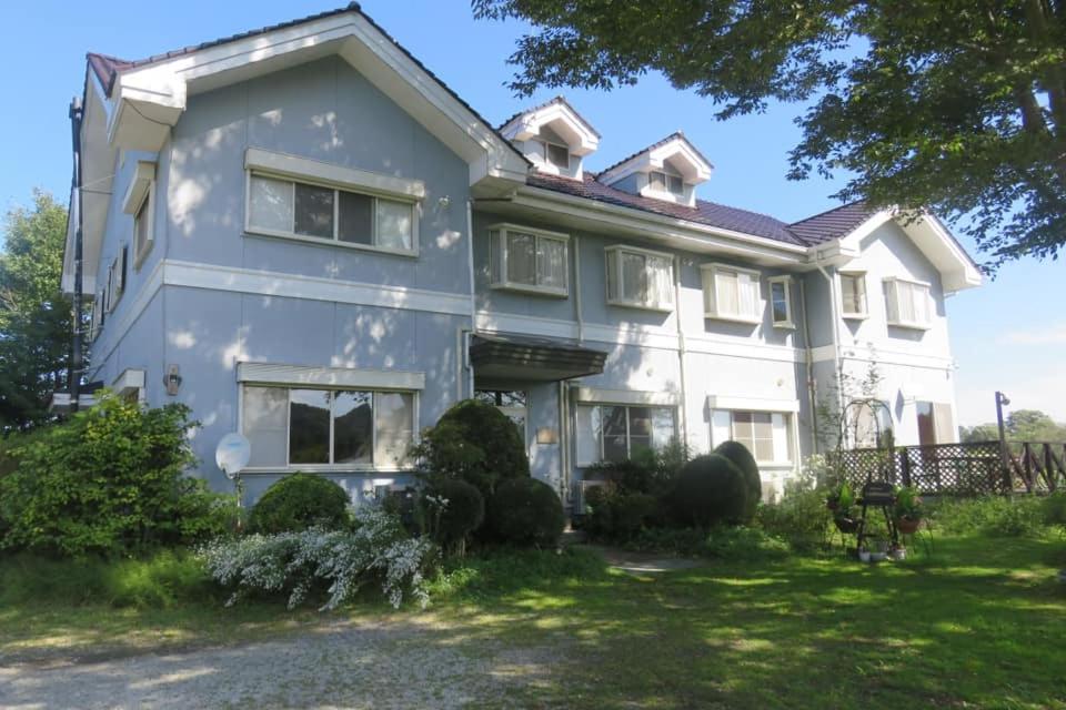 a large white house with a yard at Pension Labrador in Karuizawa