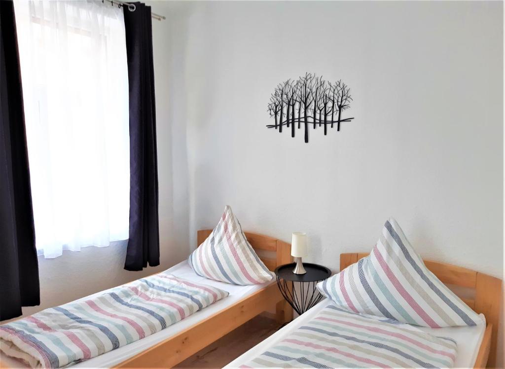 2 Betten mit gestreiften Kissen in einem Zimmer mit Fenster in der Unterkunft Citywohnung Südliche Innenstadt II in Halle an der Saale