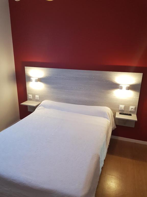 1 dormitorio con 1 cama blanca y 2 luces en Hotel Restaurant Le Bourgneuf, en Morlaas