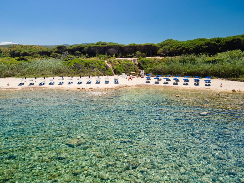 uma praia com espreguiçadeiras e água em Amareclub Red Sun Village em Isola Rossa