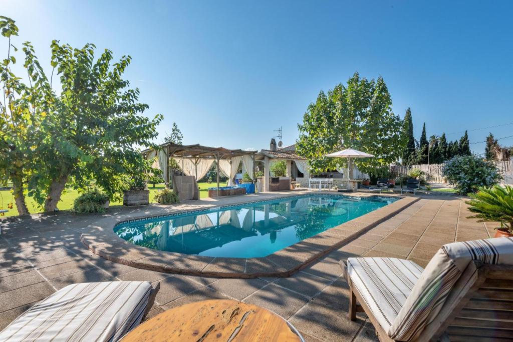 einen Pool in einem Garten mit zwei Holzstühlen in der Unterkunft Raiguer in Selva