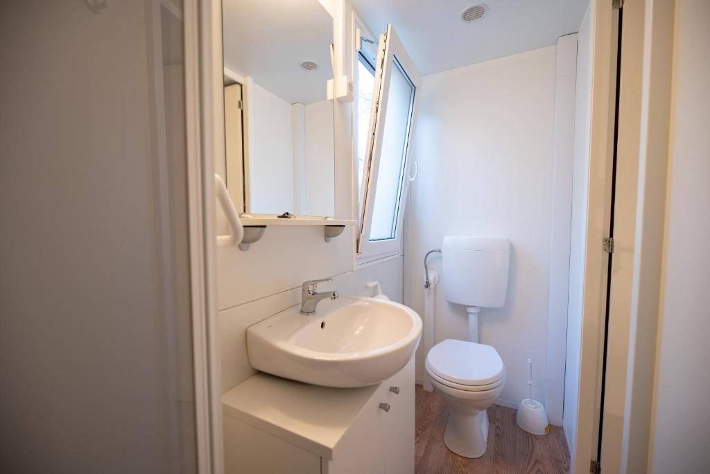 a white bathroom with a sink and a toilet at Camping Kozarica Mobile Homes in Pakoštane