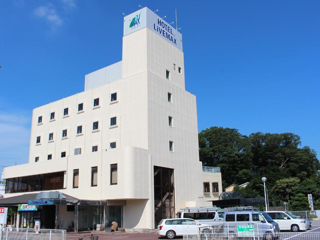 un edificio blanco con coches estacionados frente a él en HOTEL LiVEMAX BUDGET Utsunomiya, en Utsunomiya