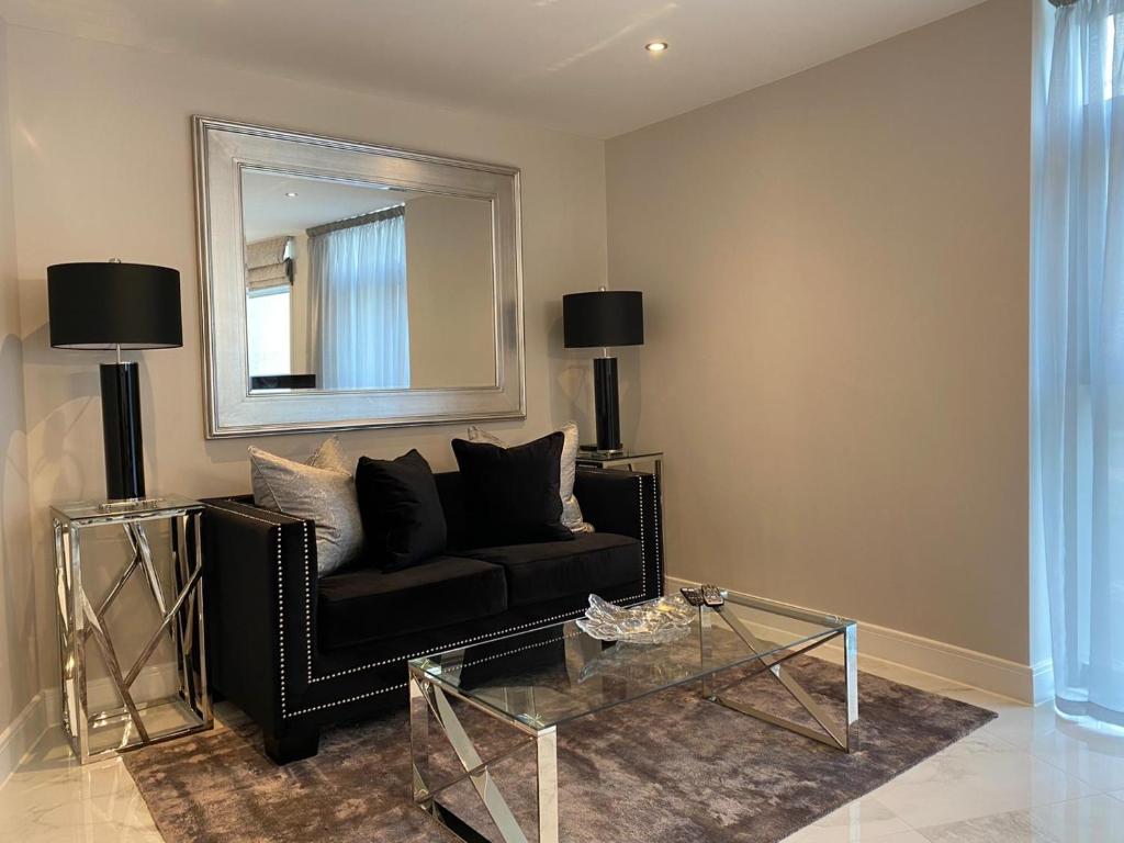 a living room with a black couch and a mirror at Exclusive Cardiff City Centre Apartment in Cardiff