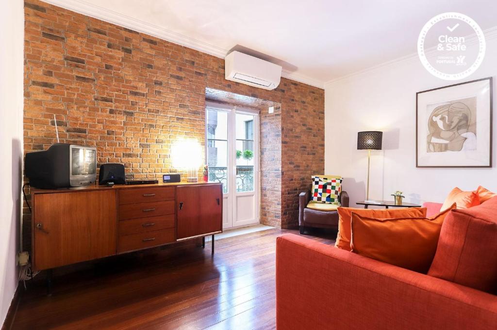 a living room with a red couch and a brick wall at Avenida da Liberdade Duplex by Homing in Lisbon