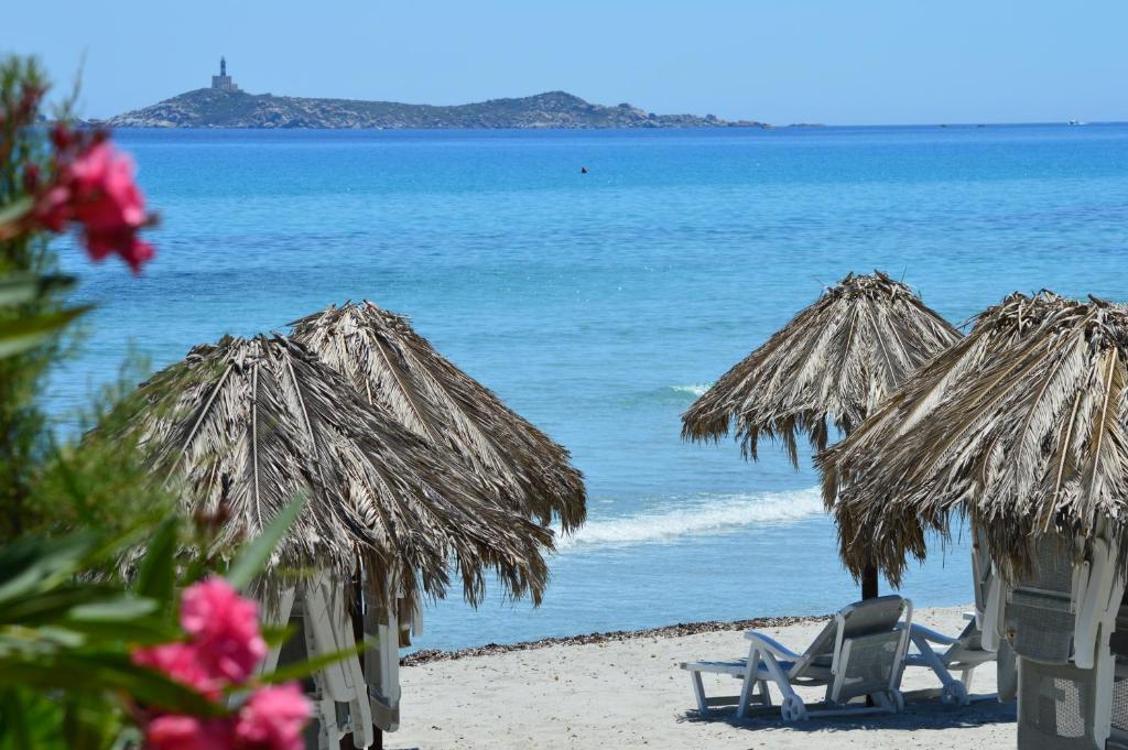two chairs and umbrellas on a beach with the ocean at Residence Fenicia in Villasimius
