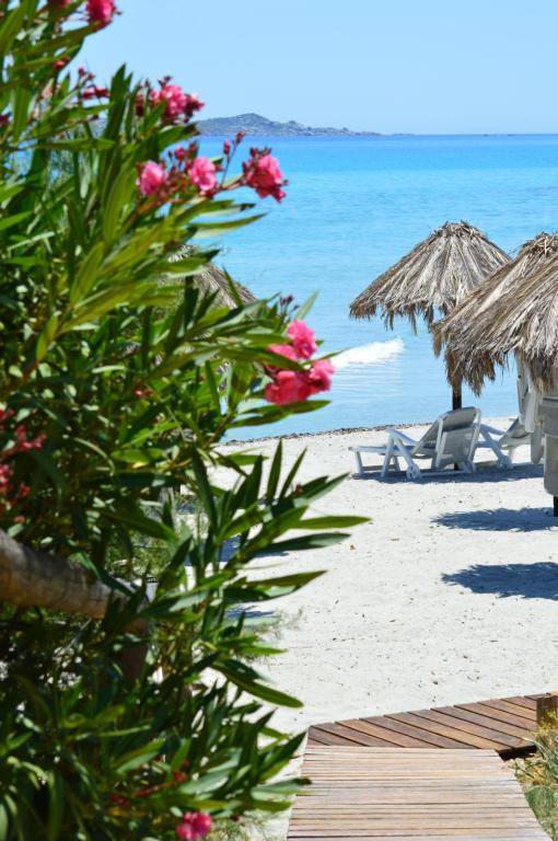 a beach with umbrellas and chairs and the ocean at Residence Fenicia in Villasimius