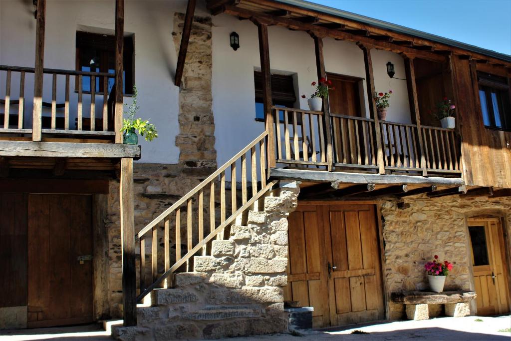 a stone building with wooden stairs and wooden doors at Alojamientos Serra da Lastra in Villar de Silva