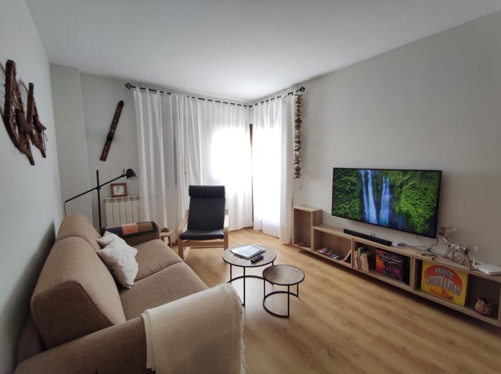 sala de estar con sofá y TV de pantalla plana en Inmocyma Cerler Prados de Velarta C 1-3, en Cerler