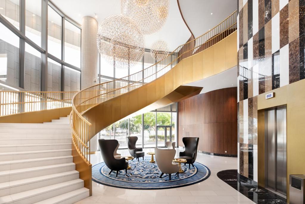 The main lobby combines a grand curved staircase, elevator bank and window-lit seating.