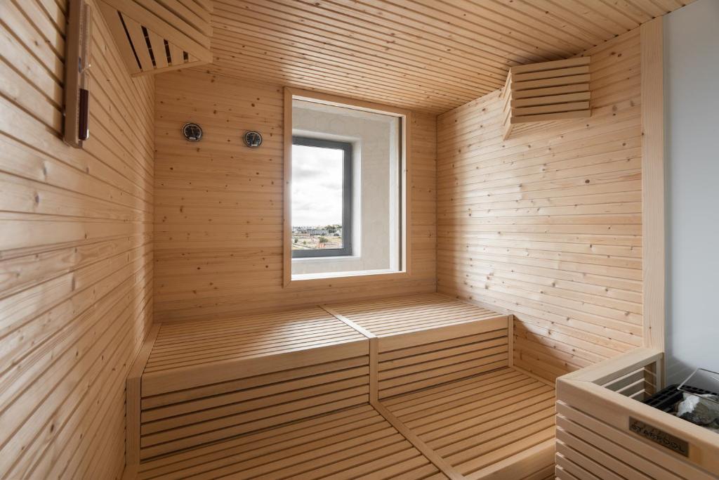 A compact wood-lined sauna with tiered benches, a window and a visible heater.