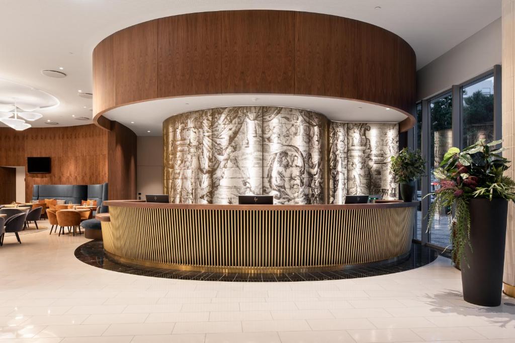 A sculptural reception desk faces a lounge and tall windows.