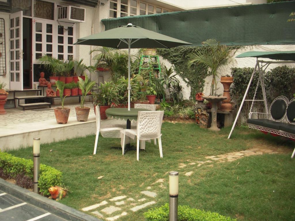 un patio con mesa, sillas y sombrilla en Rams Inn en Nueva Delhi