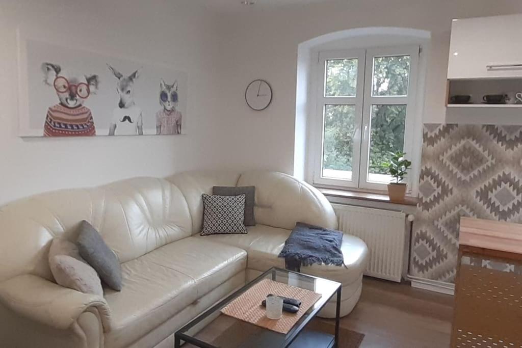 een woonkamer met een witte bank en een salontafel bij Lemuria Apartament Szkolna centrum in Legnica