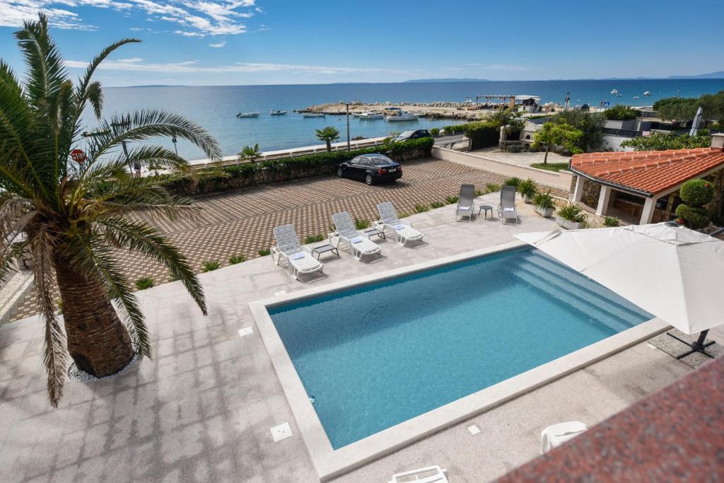 a swimming pool with a view of the ocean at Beachfront Apartments Tolo with Pool in Novalja