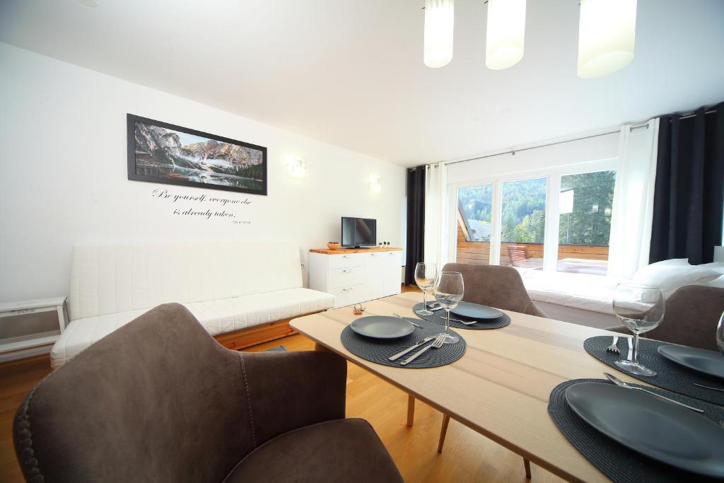 a dining room with a table and chairs and a couch at Apartma Prisank Kranjska Gora in Kranjska Gora