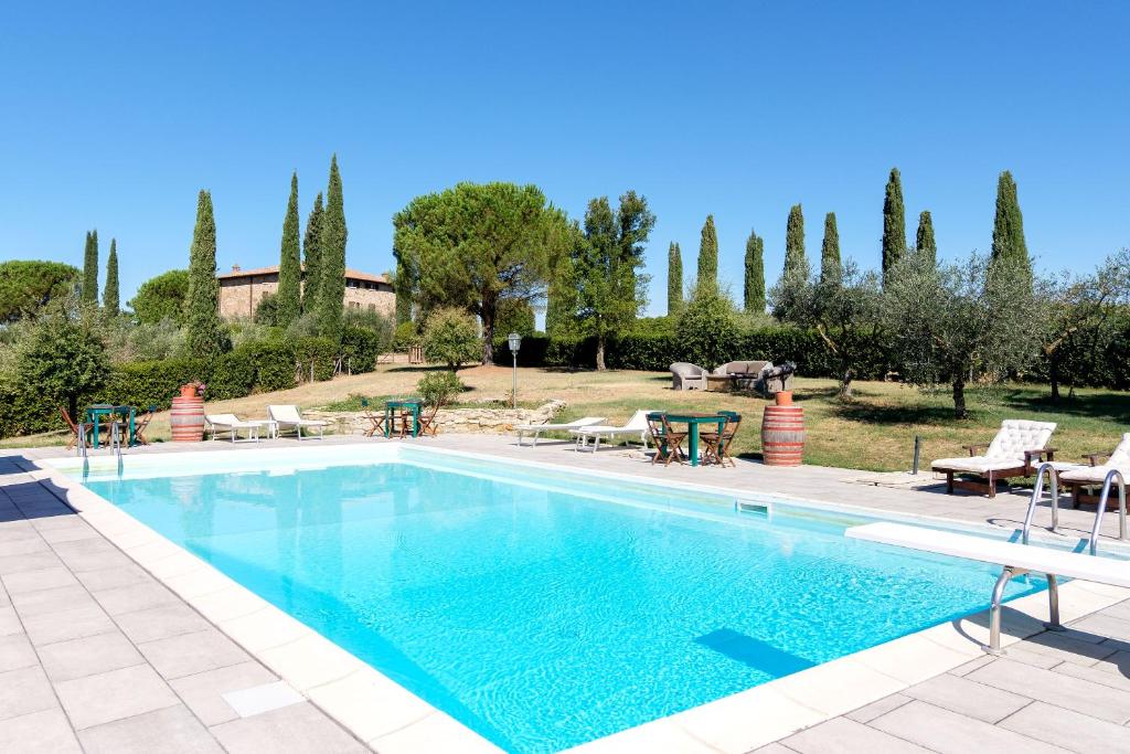 uma piscina com mesas, cadeiras e árvores em Agriturismo Cavalierino em Montepulciano