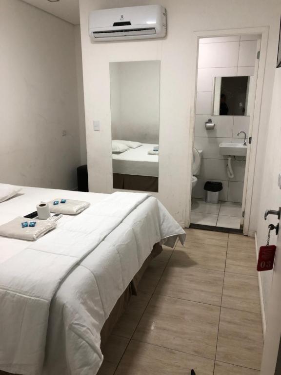 um quarto com uma cama e uma casa de banho com um lavatório em Hotel Novo Oriente Brás em São Paulo