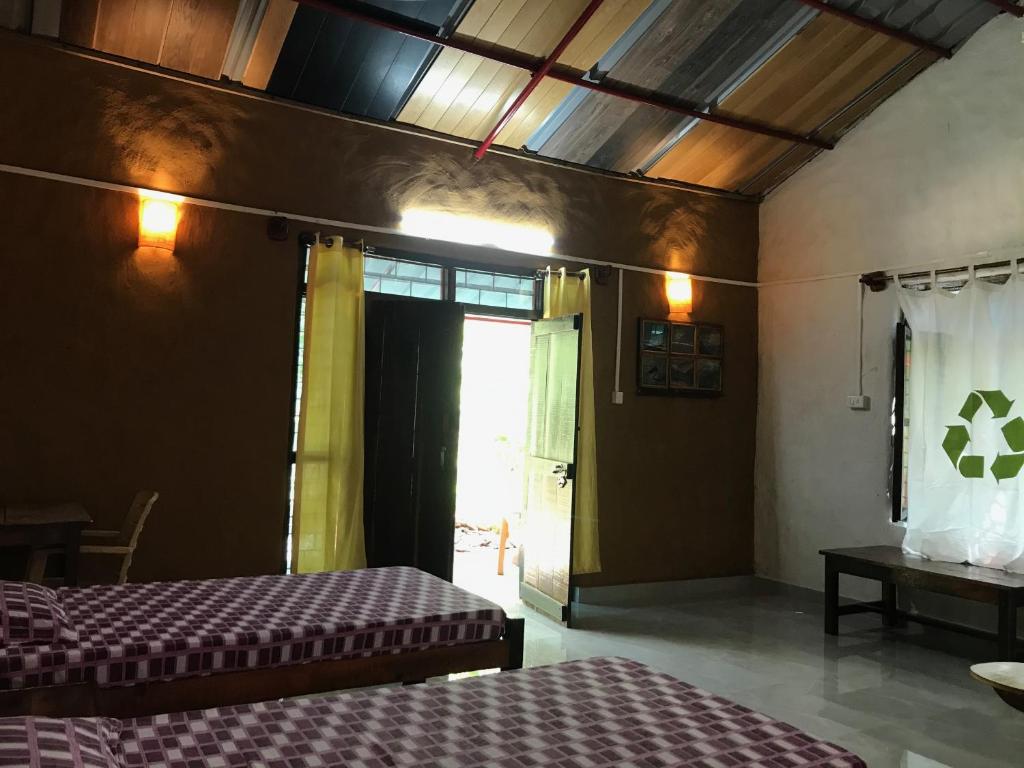 a room with two beds and a door with a window at Kamp Kamouflage Kanha in Kānha