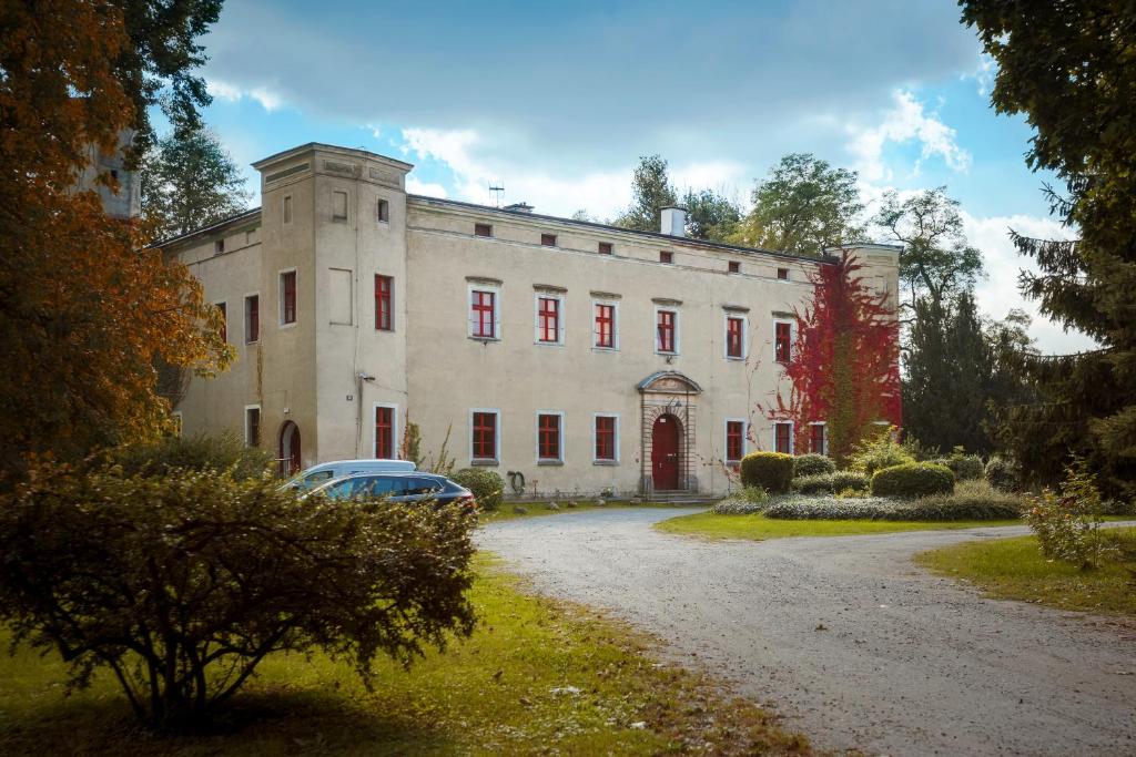 duży budynek z zaparkowanym przed nim samochodem w obiekcie Zamek Dobroszyce w mieście Dobroszyce