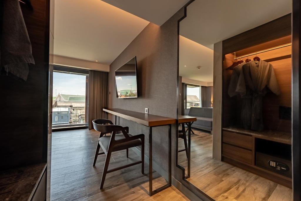 A built-in work counter beside a chair, wardrobe, mirror, and city-facing window.