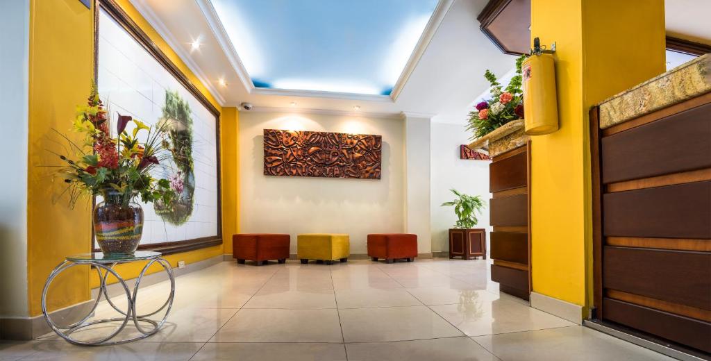 a lobby with yellow walls and a vase of flowers on a table at HOTEL AMERICANA PASTO in Pasto