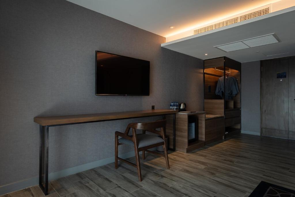 A slim in-room work desk beneath a wall-mounted television, beside storage and a minibar.