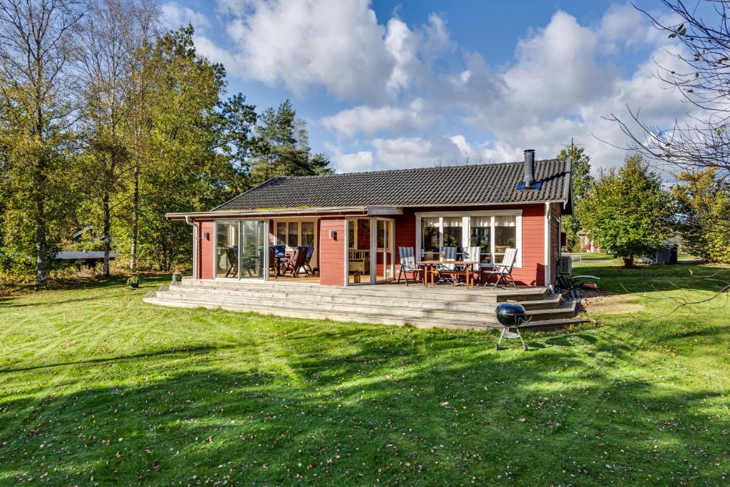 una pequeña casa con terraza y patio en Nice holiday house in Knared, en Knäred