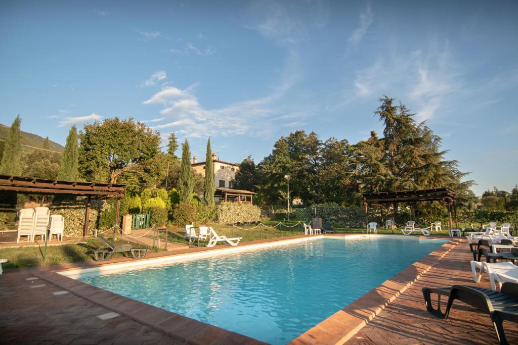 a large swimming pool with chairs and a house at Agriturismo Sasso Rosso in Capodacqua