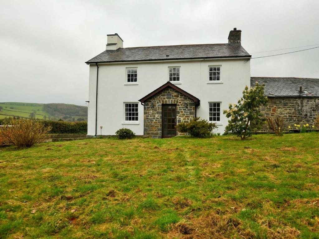een oud wit huis met een grasveld bij Pengarreg Fawr in Aberystwyth