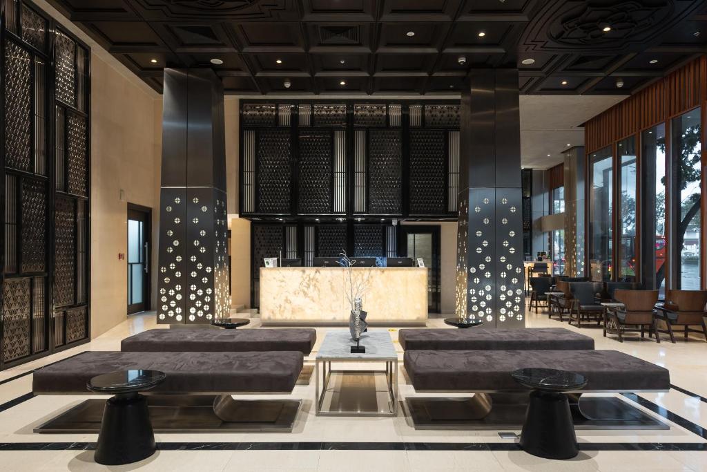 A polished hotel lobby with a marble reception desk and low lounge seating.