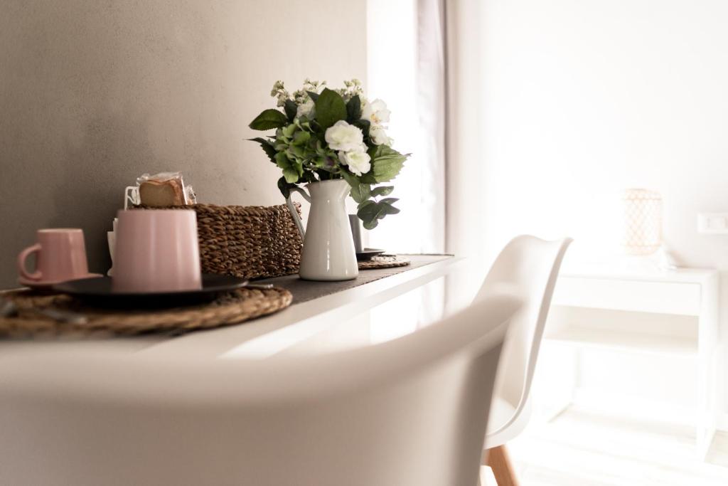 a table with a vase of flowers and a plate at Via Mazzini B & B (MXP) in Vizzola Ticino