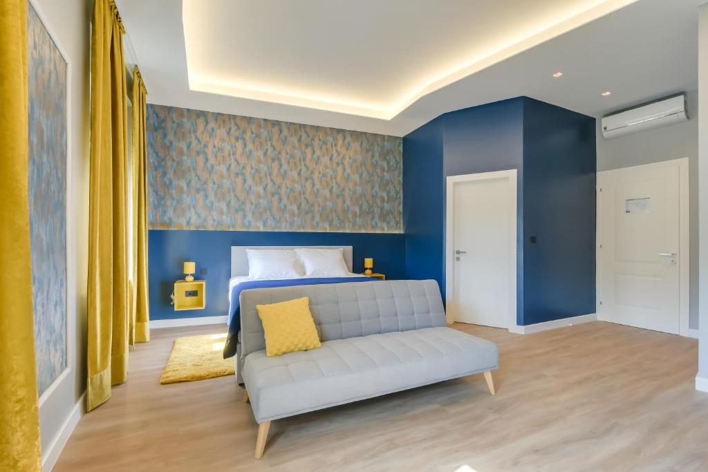 a bedroom with blue walls and a bed with a couch at Royal residence Zagreb in Zagreb
