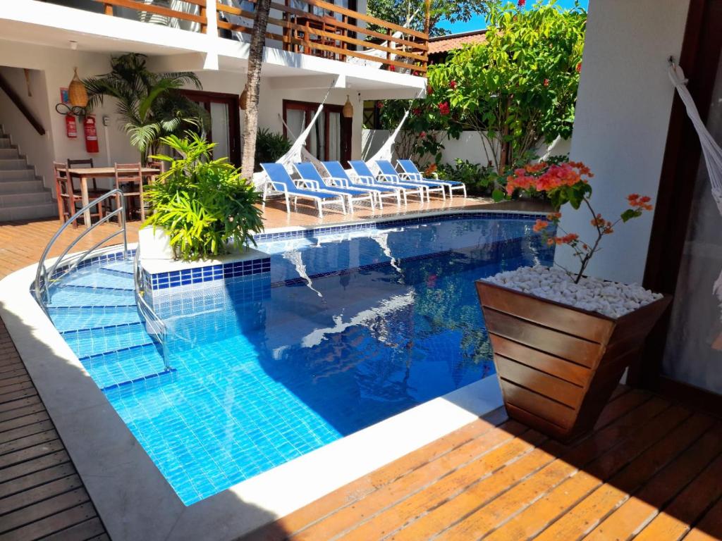 a swimming pool with chairs next to a house at Pousada Waikiki Boutique in Pipa