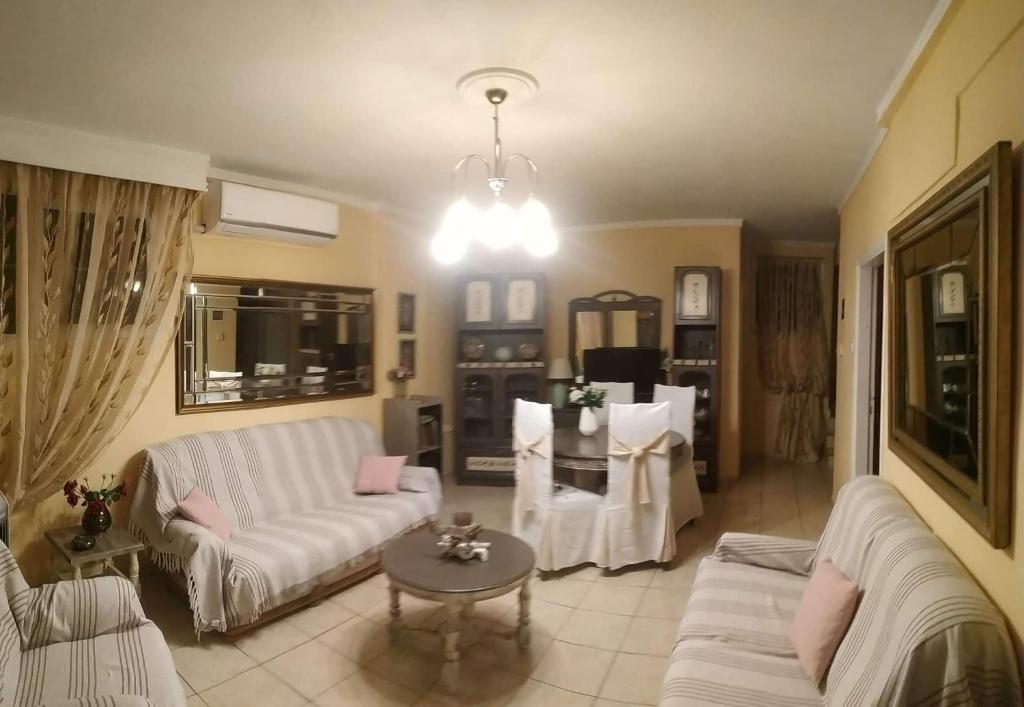 una sala de estar con sofás blancos y una mesa. en Anthi Apartment, en Palaión Tsiflíkion