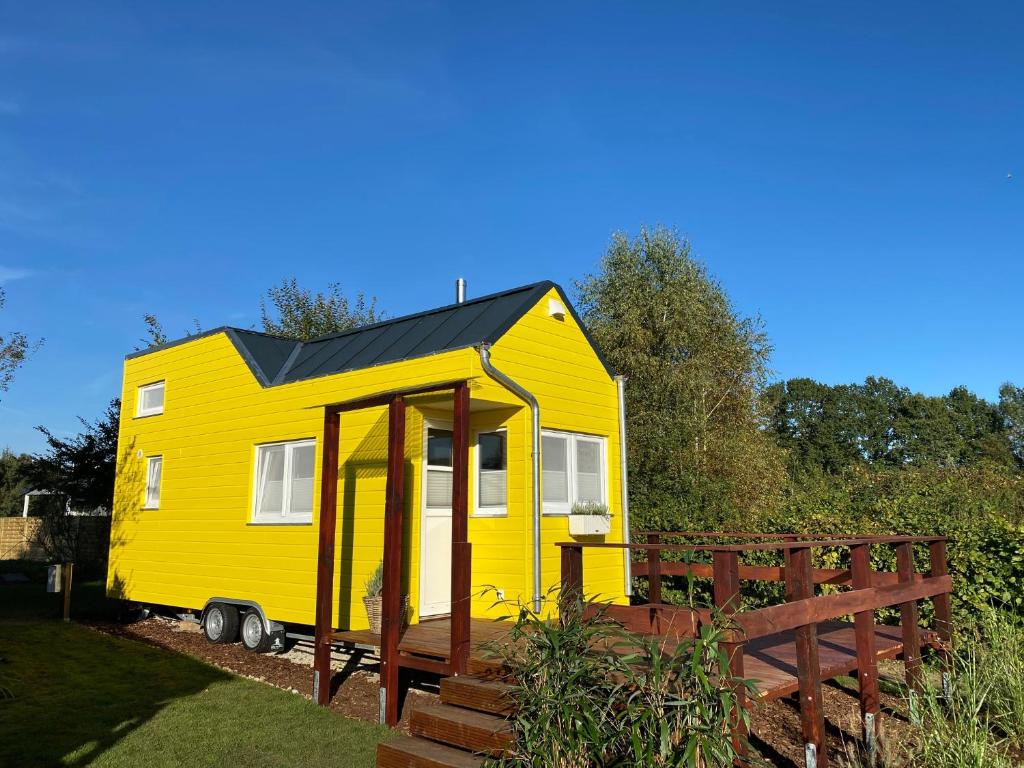 a yellow tiny house is parked in a yard at Ferienhaus Tiny Löwenzahn in Visselhövede